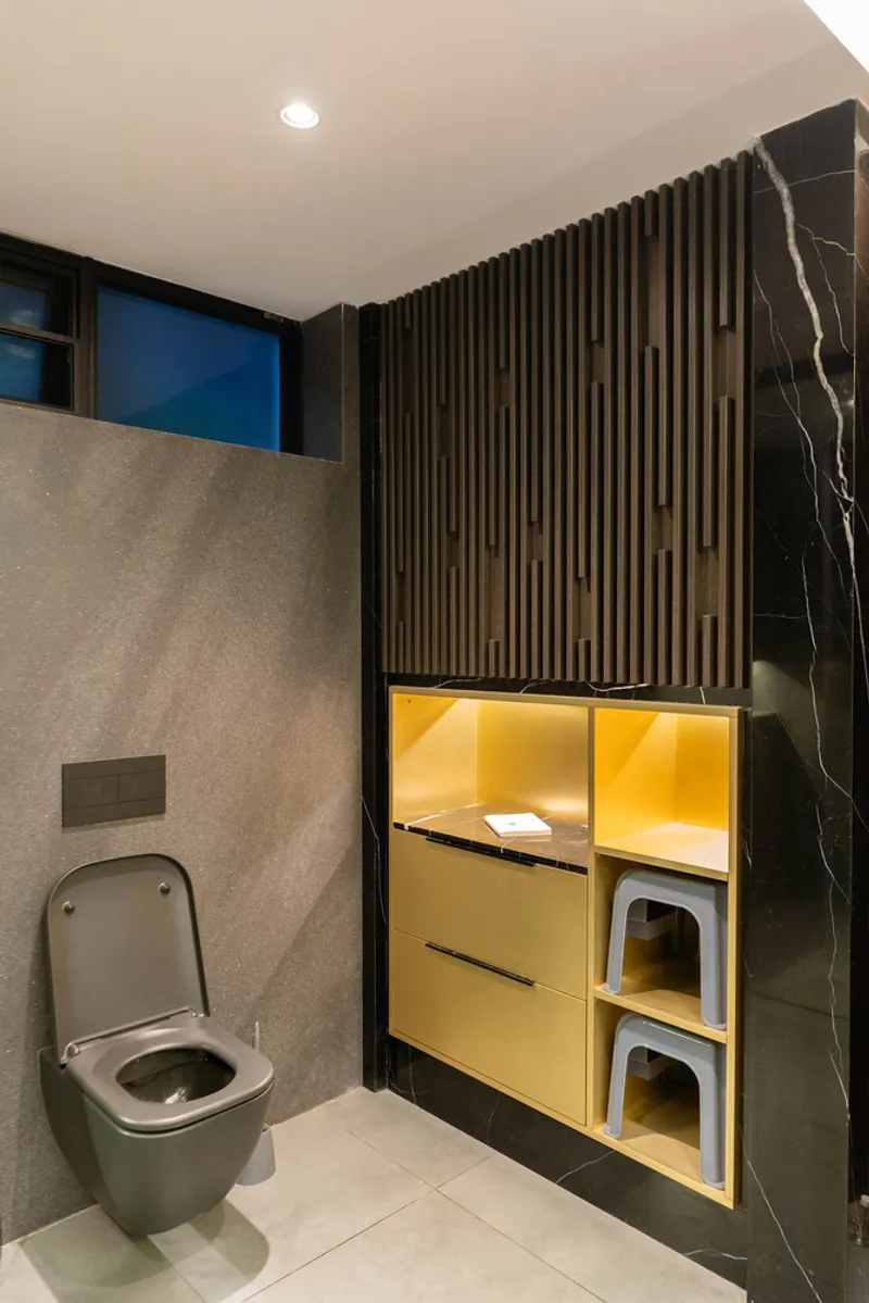 Bathroom interior with vertical timber slat wall, yellow illuminated storage niche, and grey terrazzo partition