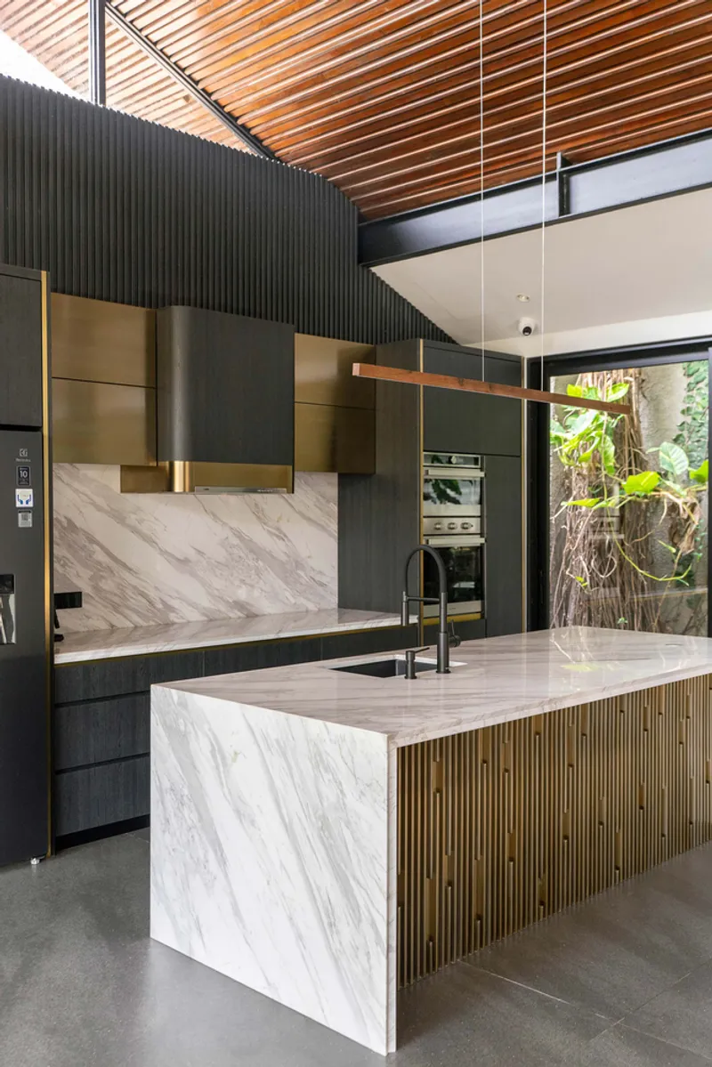 Kitchen island with marble cladding and fluted timber detailing beneath a radiating timber slat ceiling