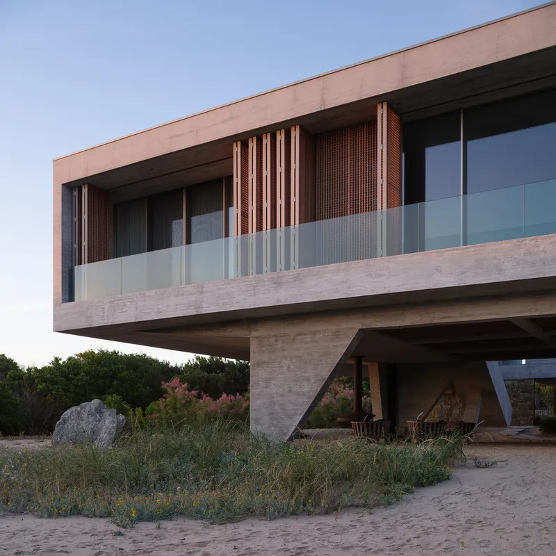 Sunset facade: concrete edge beam, timber louvre screen, glass balustrade, V-column, large boulder, warm evening light
