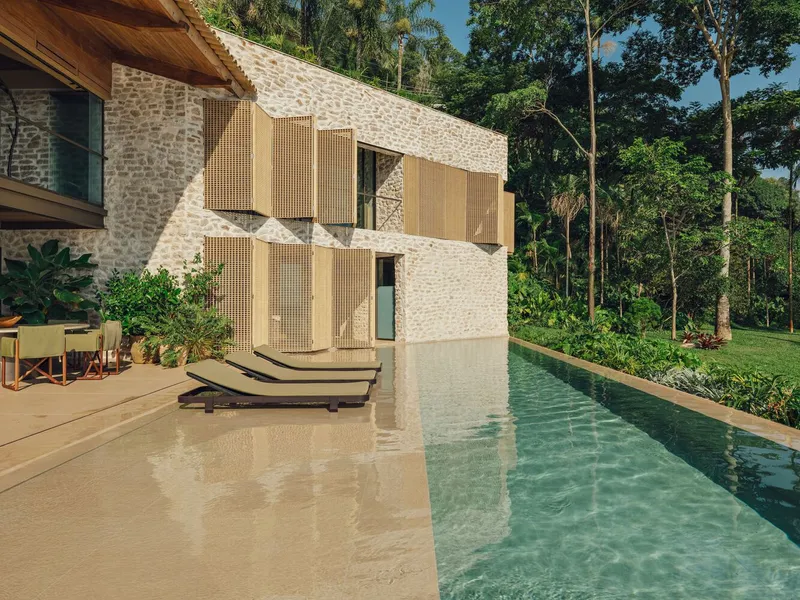 Stone facade with timber shutters and lap pool against dense tropical vegetation