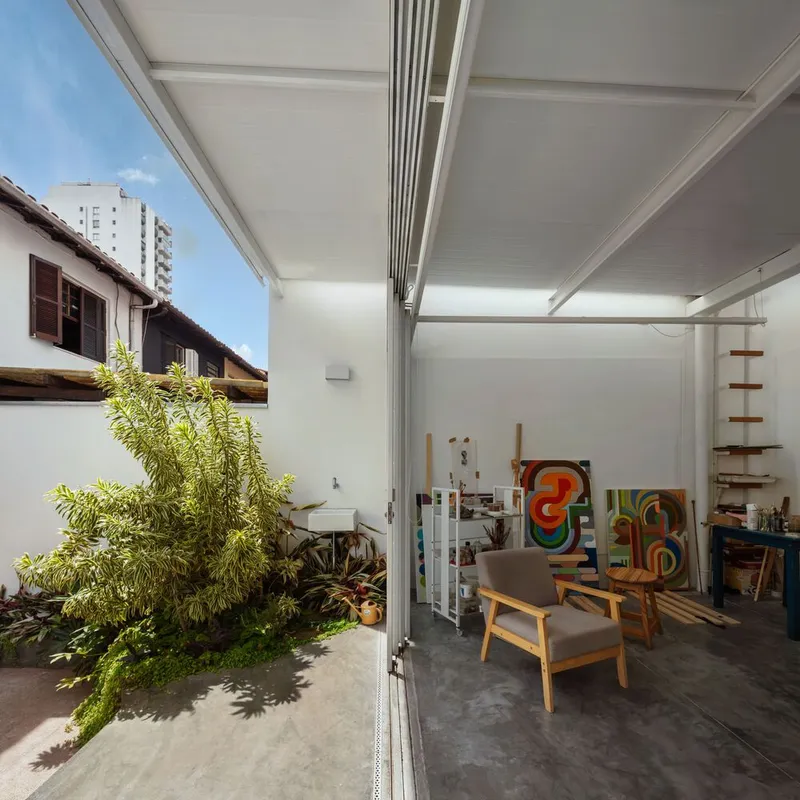 Storage wall: canvases stacked against the white wall, wooden ladder leaning toward mezzanine shelf