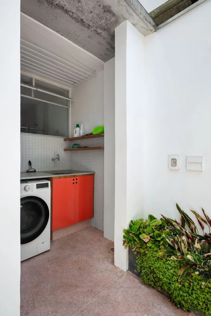 Corridor with dog: pink terrazzo floor, white walls, plywood door, pendant light, golden retriever lying in the doorway