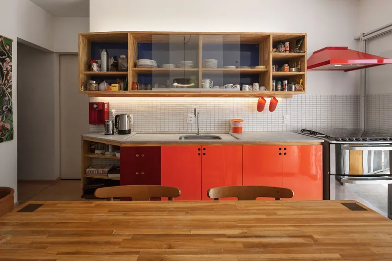 Laundry: compact utility space with red cabinet door, washing machine, concrete sink, green wall planting