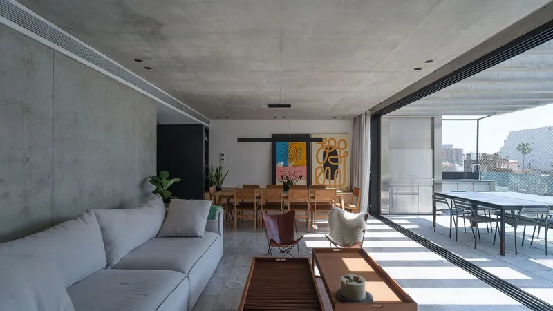 Open-plan living and dining space with exposed concrete ceiling and full-height sliding glass doors to terrace