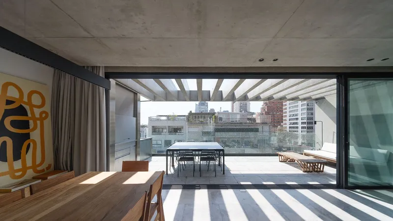 Timber pergola beams casting striped shadows across the interior floor through the open terrace threshold