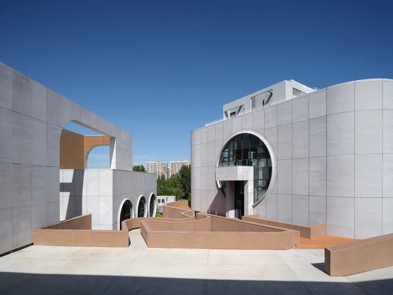 Street elevation: stacked white and brick volumes with curved balconies, cantilevered forms, glass curtain wall at base