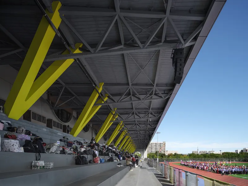 Facade detail: concentric circular relief sculpture in concrete panel, large circular window, sports centre beyond