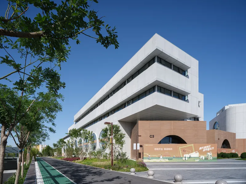 Cultural centre from park: white volume with concentric circle reliefs, landscaped slope, visitors on steps