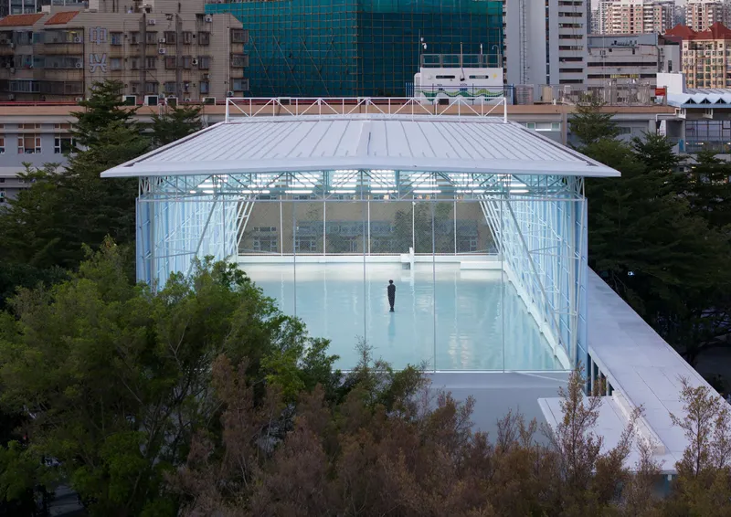 Elevated view of the glass-enclosed roof terrace with white metal roof and a solitary figure inside