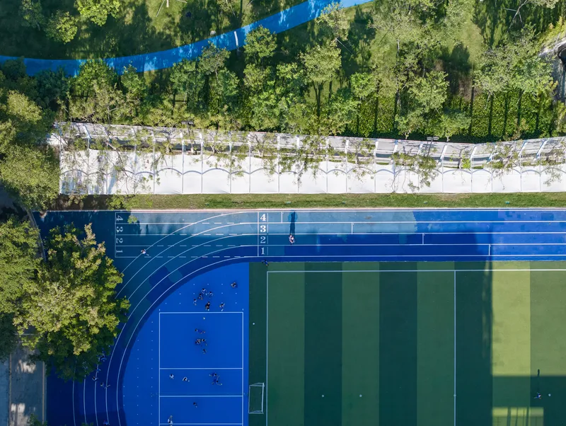 Aerial view of blue running track and sports courts bordered by a white pergola structure