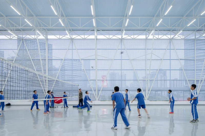 Volleyball game in progress beneath white structural trusses and translucent perforated wall panels