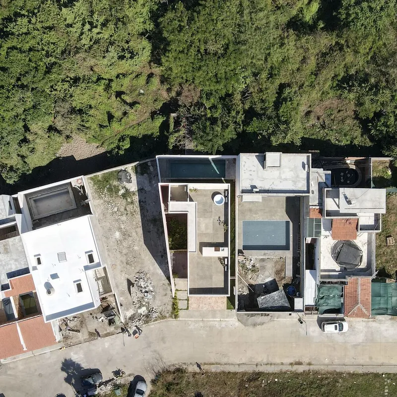 Aerial view of flat-roofed residence with courtyards and pools surrounded by dense vegetation