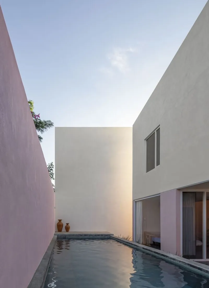 Lap pool between rendered volumes with two ceramic vessels at the water's edge at dusk