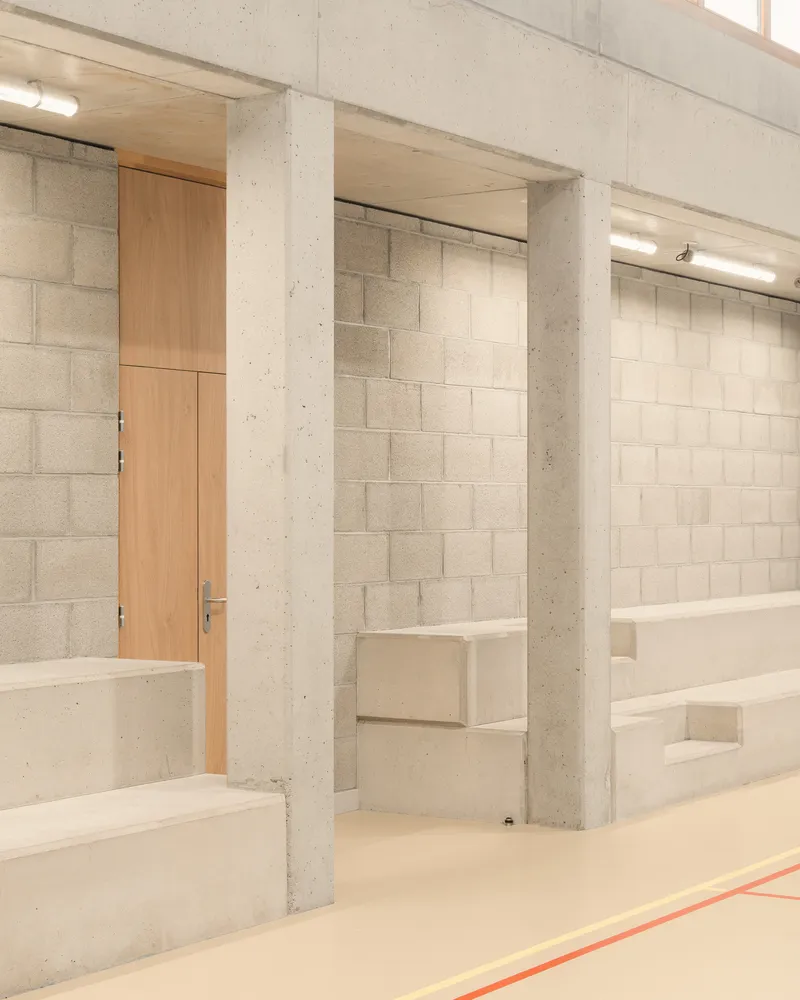 Gymnasium entrance: concrete block walls, concrete columns, timber door, built-in bench
