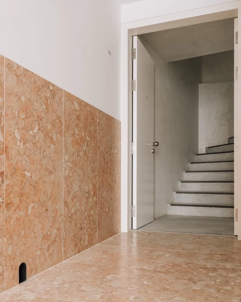 Cork panel wall alongside an open doorway revealing concrete stairs in natural light
