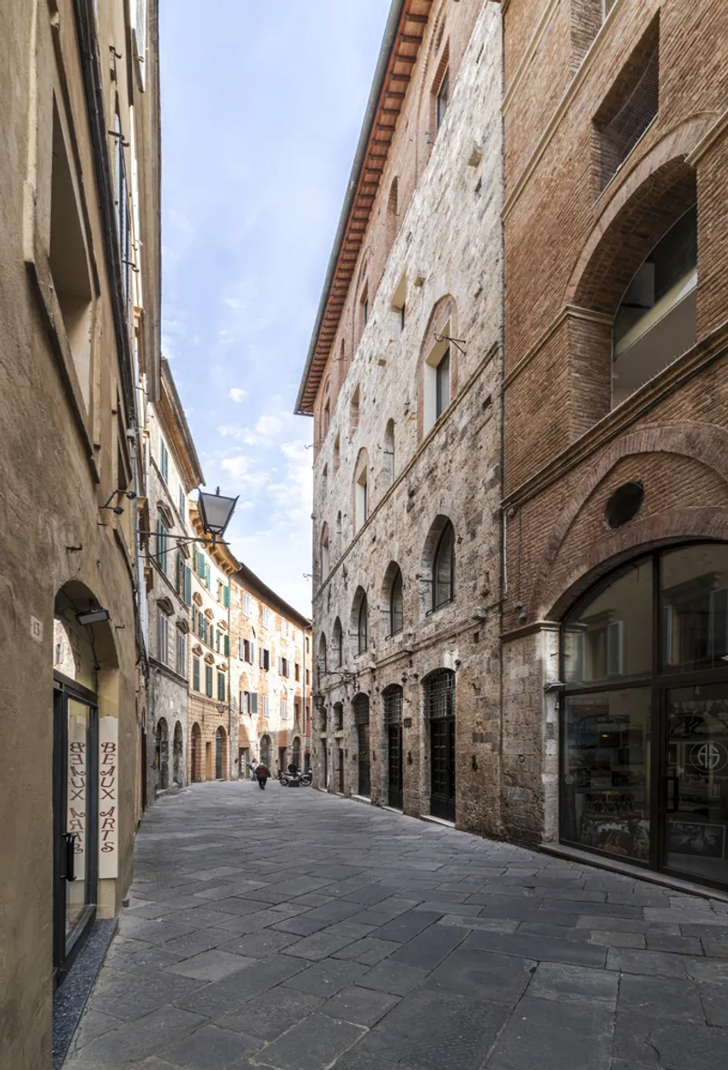 Narrow street lined with stone and brick facades under a clear afternoon sky