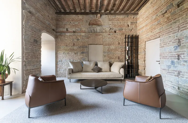 Living room with exposed brick walls and timber ceiling beams under a woven pendant light