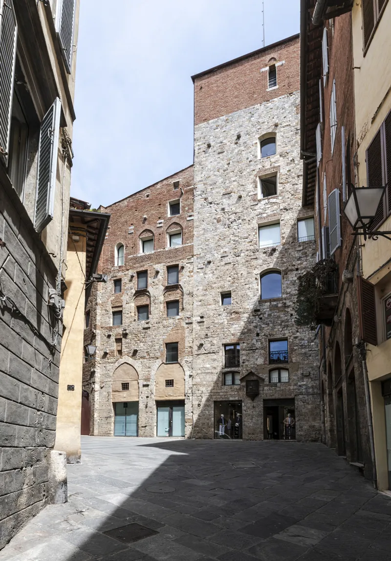 Courtyard enclosed by tall stone tower facades with arched windows and openings