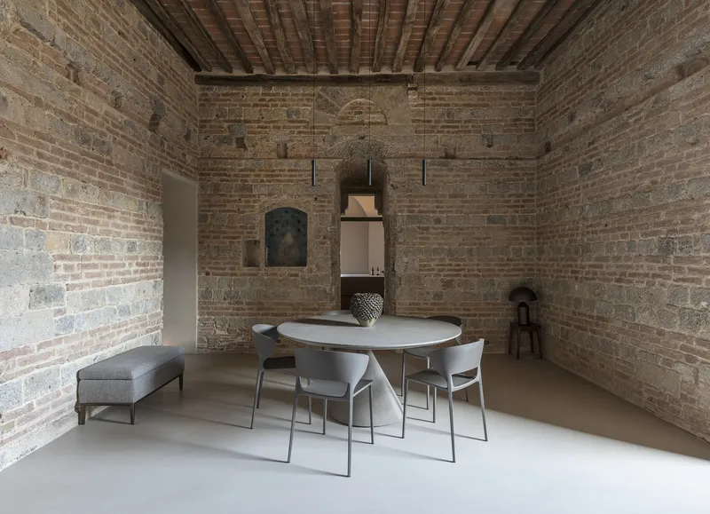 Dining area with round white table against exposed brick walls and timber ceiling