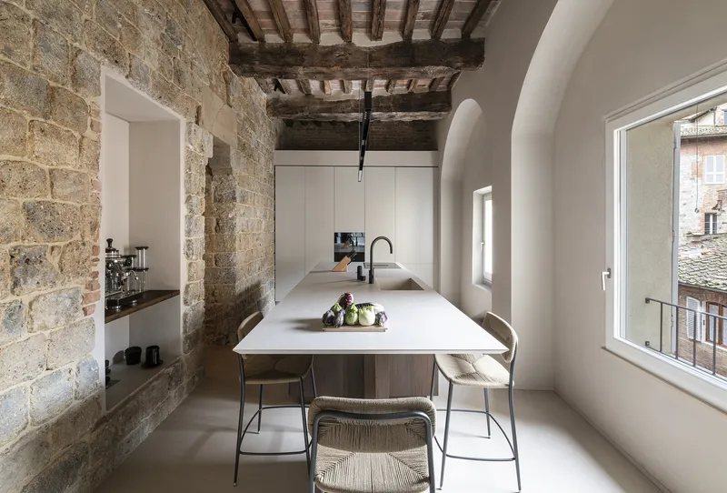 Kitchen island with white countertop framed by arched openings and exposed brick walls