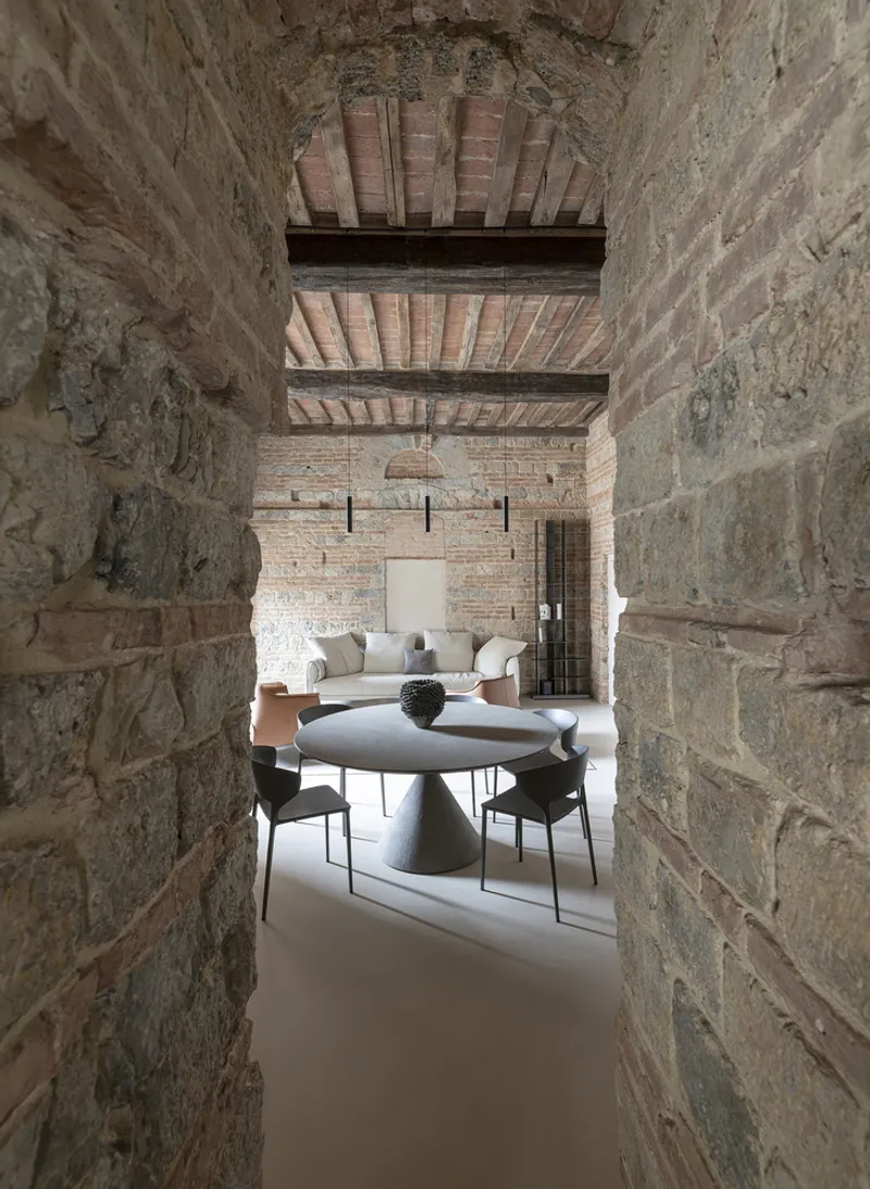 View through the stone archway toward the dining area with exposed timber beam ceiling