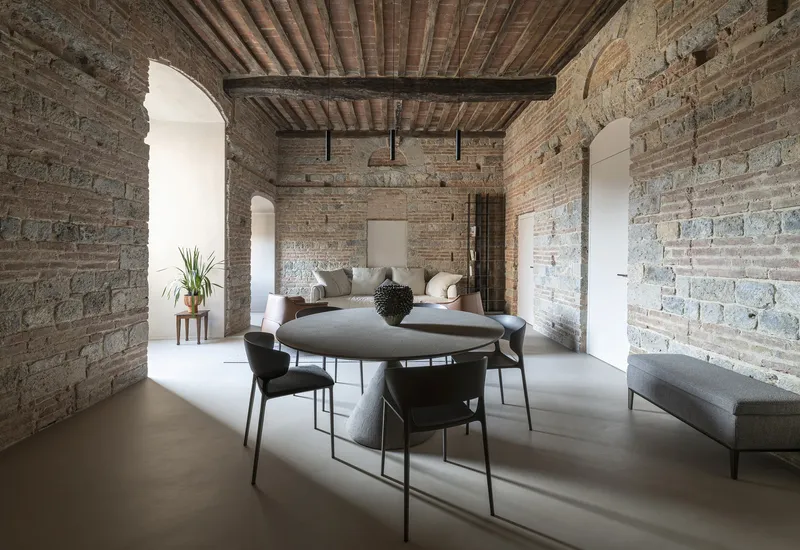 Open room showing arched doorways in the brick walls and timber plank ceiling above