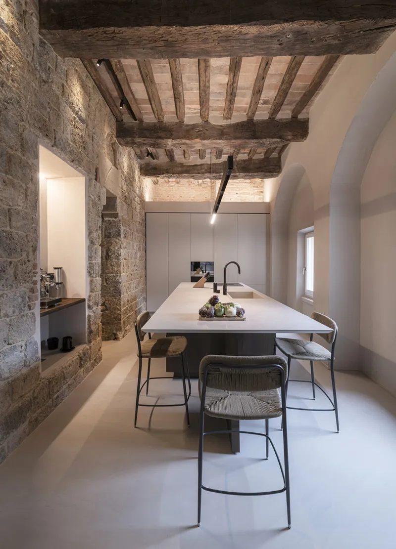 Kitchen island with bar stools under the restored timber beam and brick vault ceiling
