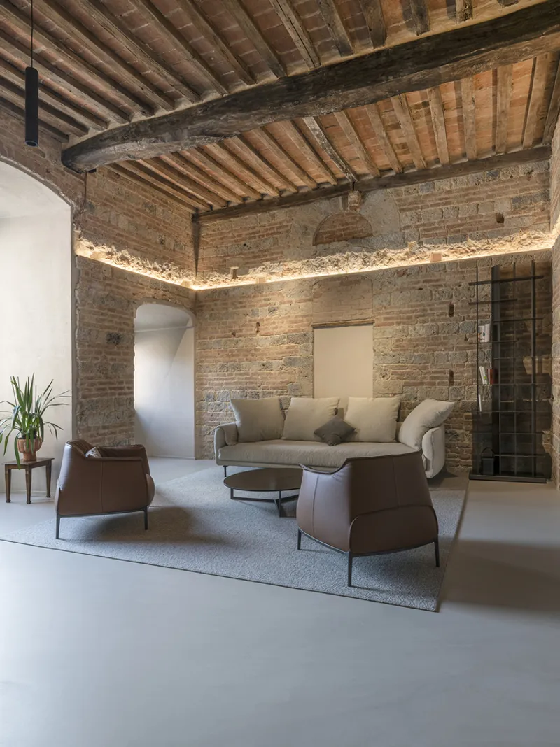 Seating area with leather armchairs beneath continuous uplighting along the brick wall perimeter