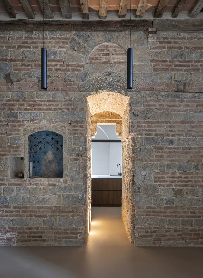 Arched passage cut through the brick wall with warm light illuminating the threshold