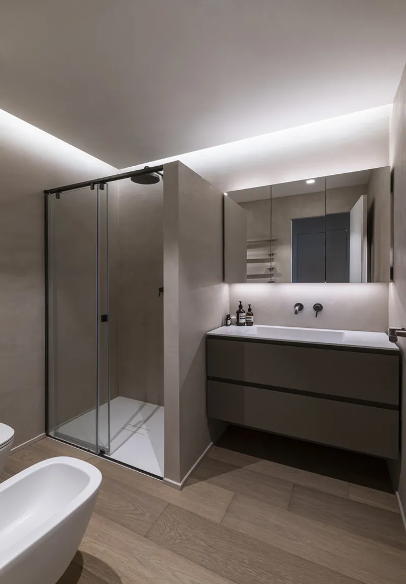 Bathroom with glass shower enclosure, floating vanity and backlit mirror under indirect cove lighting