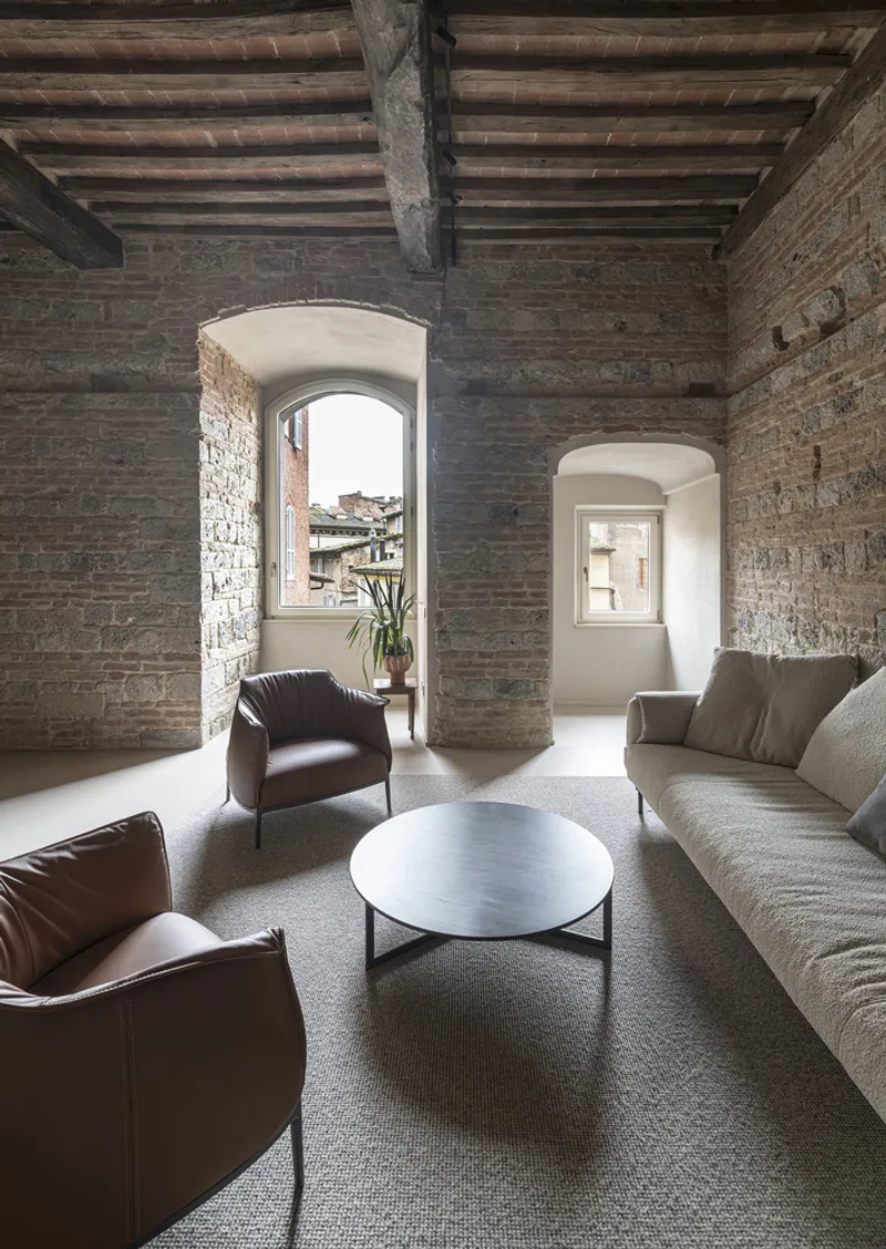Living room with exposed brick walls and arched window openings under timber beam ceiling