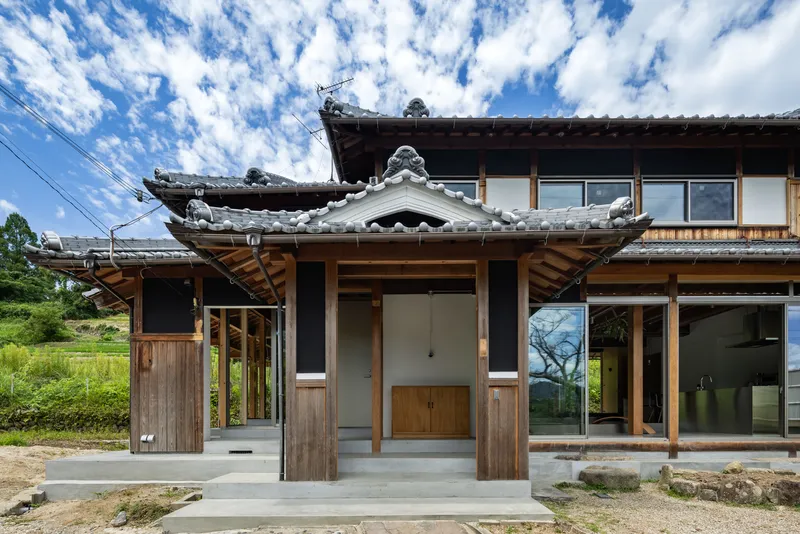 Covered entry porch with timber posts and traditional tiled roof beneath a partly cloudy sky