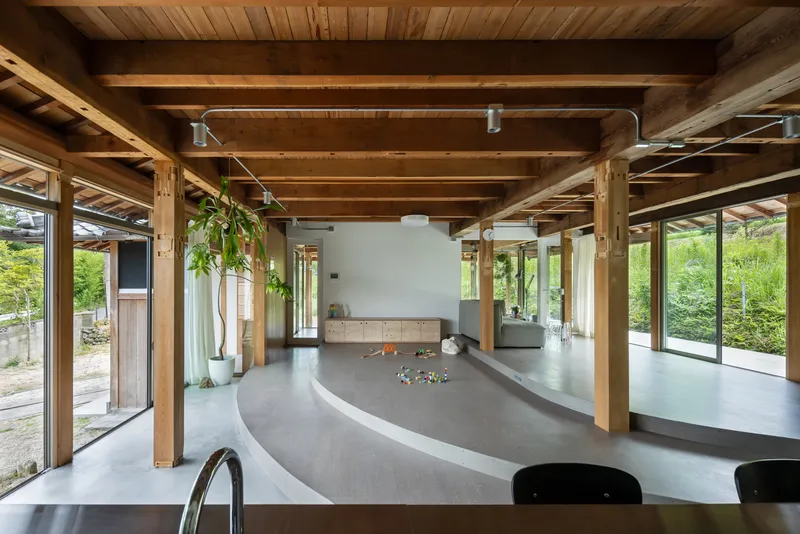 Timber-framed interior with plank ceiling, curved concrete floor and hanging potted plants throughout the space