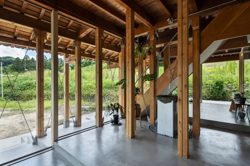 Entrance zone with timber frame structure, glazed walls and concrete floor opening to rural landscape