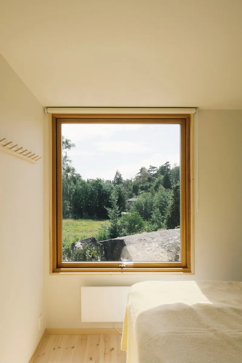 Timber-framed window opening onto a grassy meadow with distant trees under overcast skies