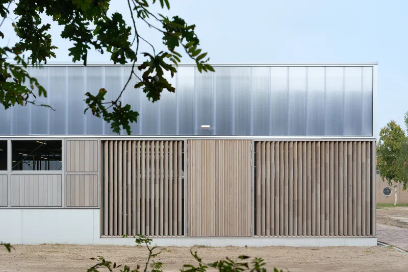 Close-up: timber slat facade panel with polycarbonate wall rising above