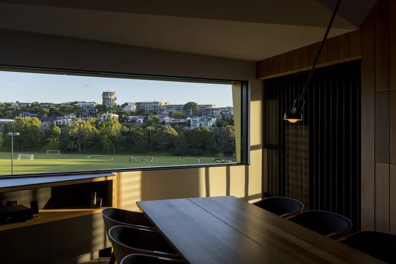Dining area with horizontal window framing distant parkland views in late afternoon sunlight