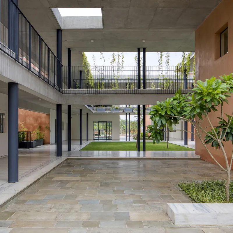 View from covered walkway showing grass courtyard with trees and circulation balconies on multiple levels