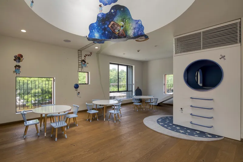 Activity room with painted ceiling cloud detail and curved blue entry steps under timber batten grilles