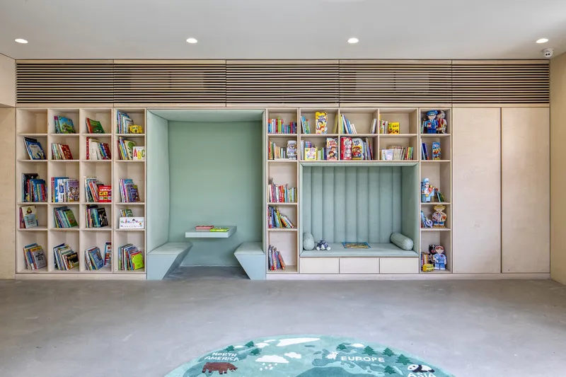 Built-in bookshelf wall with twin reading nooks upholstered in mint green fabric and recessed downlights