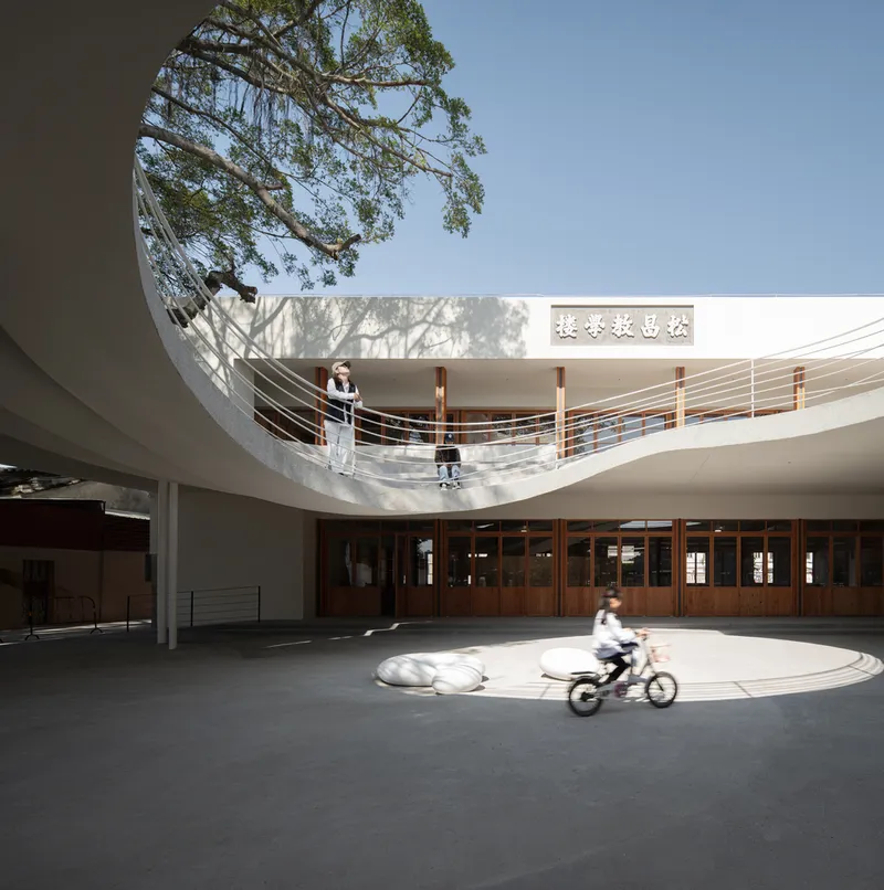 Curved balcony overlooking the circular courtyard with students and dappled tree shadows