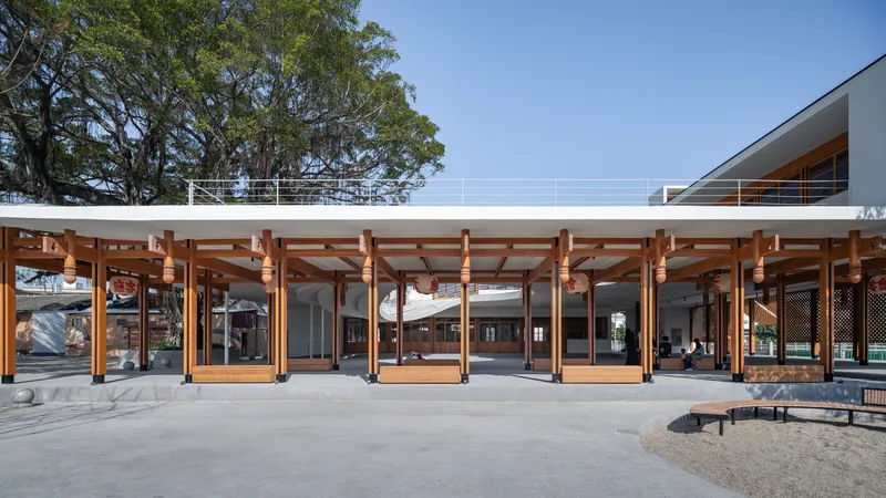 Covered courtyard with exposed timber post-and-beam structure and glazed doors under a clear blue sky