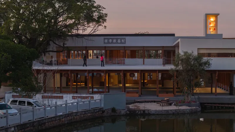 Two-story facade with timber-framed glazing and balcony overlooking a canal at dusk