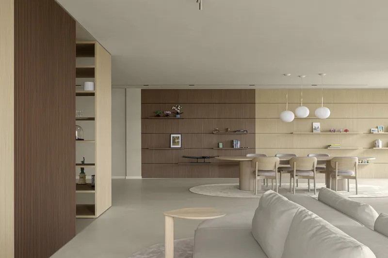 Open-plan living area with wood-paneled walls, built-in shelving, and a dining zone under pendant lights
