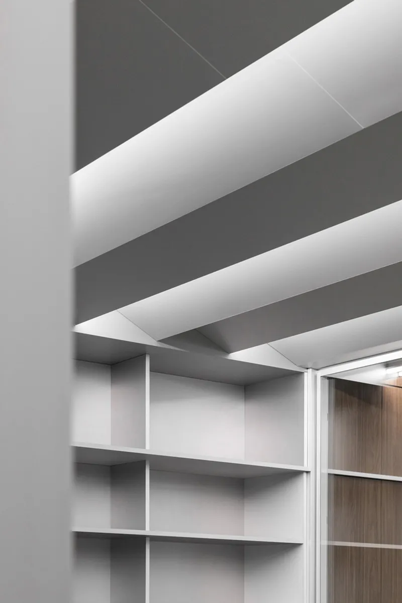 Ceiling: white baffles with gaps between, grey structure above, shelving unit edge at the corner