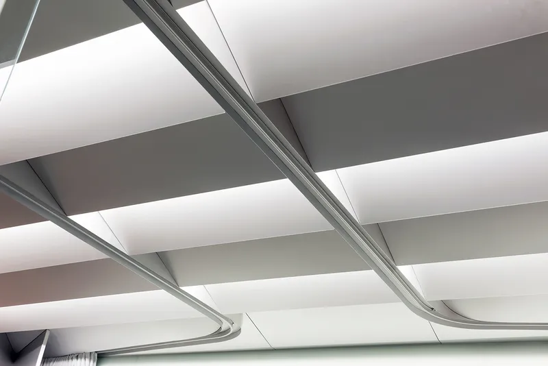 Ceiling detail: white acoustic baffles, aluminium conduit running between them