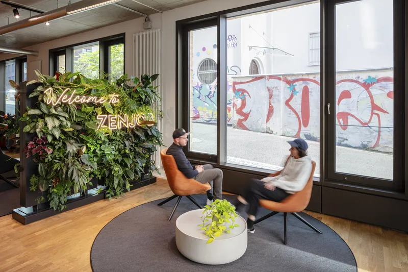 Seating area beside full-height windows overlooking the street with a living wall and neon signage