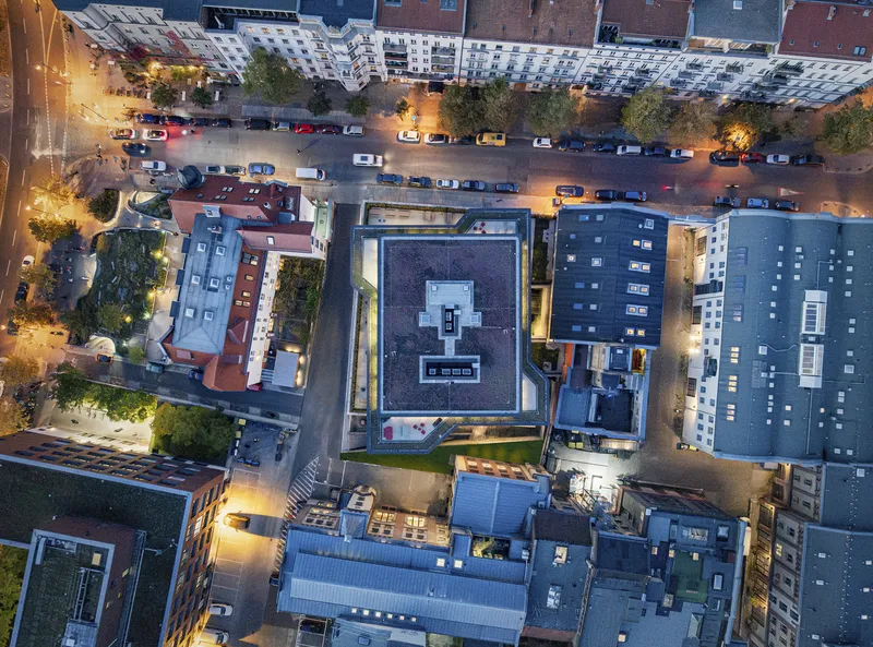 Drone view at dusk showing the rooftop courtyard and streetlights along the adjacent boulevard