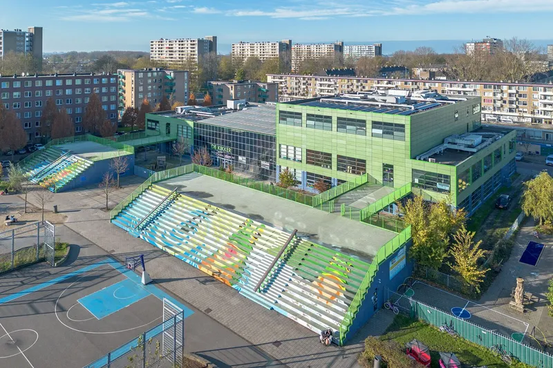 Aerial view of the tiered seating structure and adjacent basketball courts surrounded by residential towers