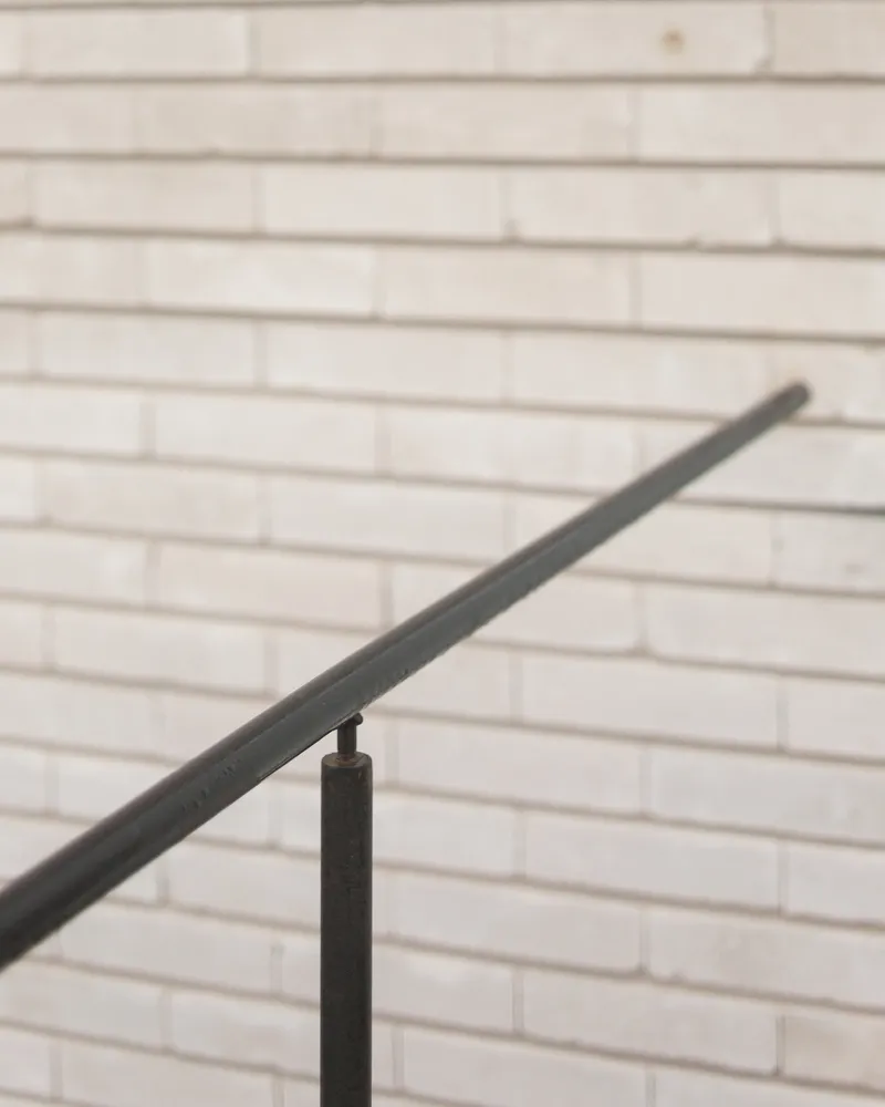 Handrail detail: black steel railing against pale brick wall